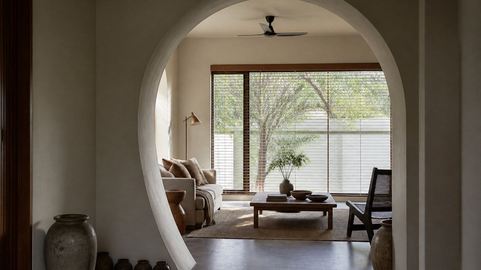 Plaster arch opening into a contemporary Indian living room with daylight modelling the curve
