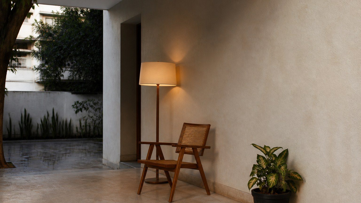 Quiet residential corner: chair, lamp, a finished wall, evening shade