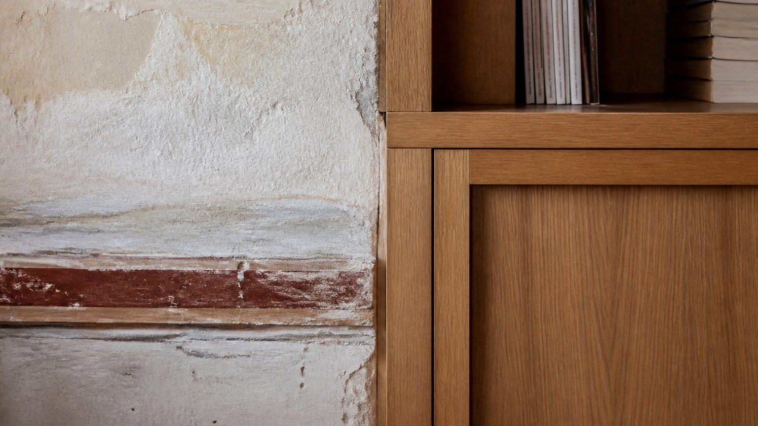 Detail where new timber millwork meets weathered plaster in an older interior