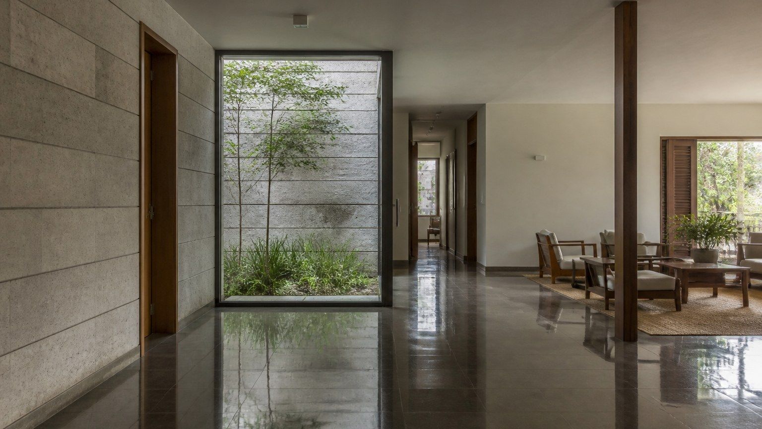 Polished stone floor, glass and timber in a contemporary Indian interior, daylight reflected without glare