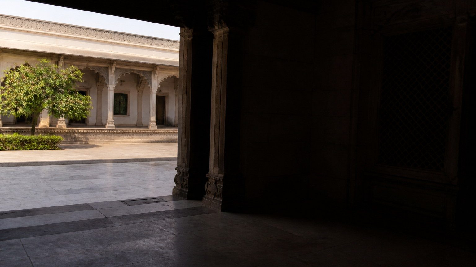 Threshold where bright Indian daylight meets a deeply shaded interior
