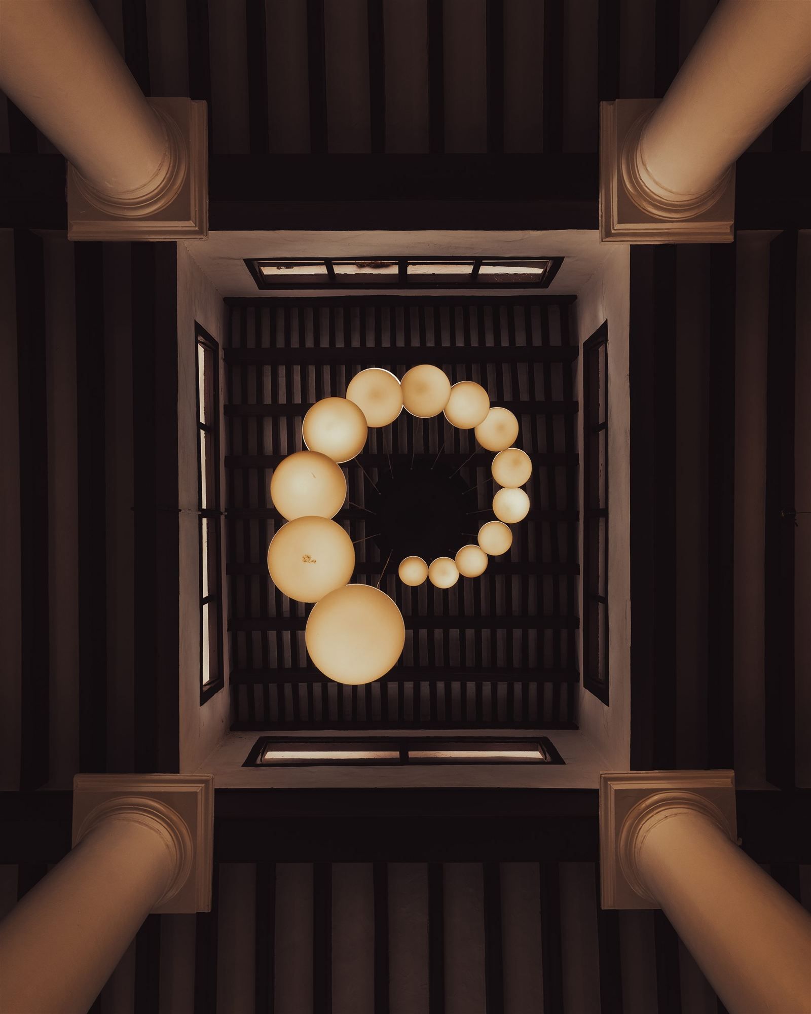 Spiral pendant chandelier viewed from below the wood-beamed ceiling