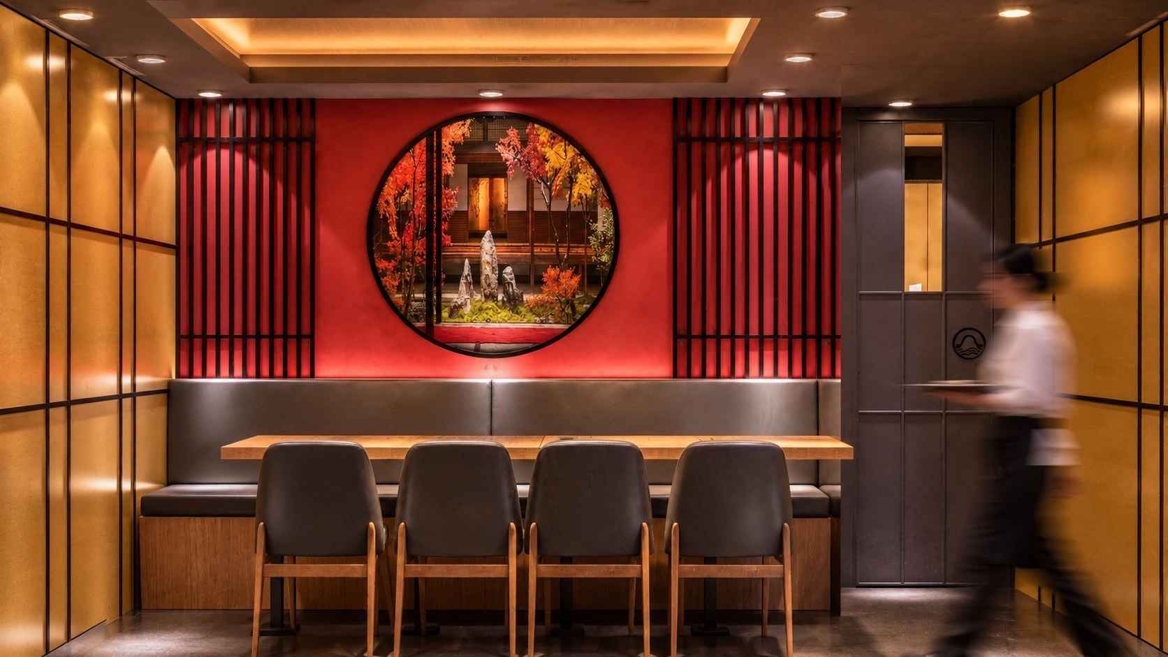Circular red-lacquer window framing a garden view at Kazan Japanese Ramen