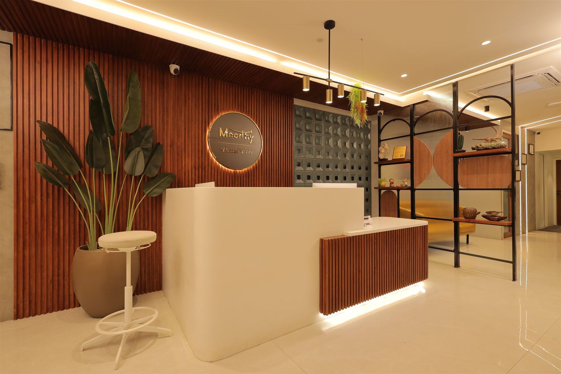 Backlit reception desk with warm wood slat wall at Moorthy Dental Elite