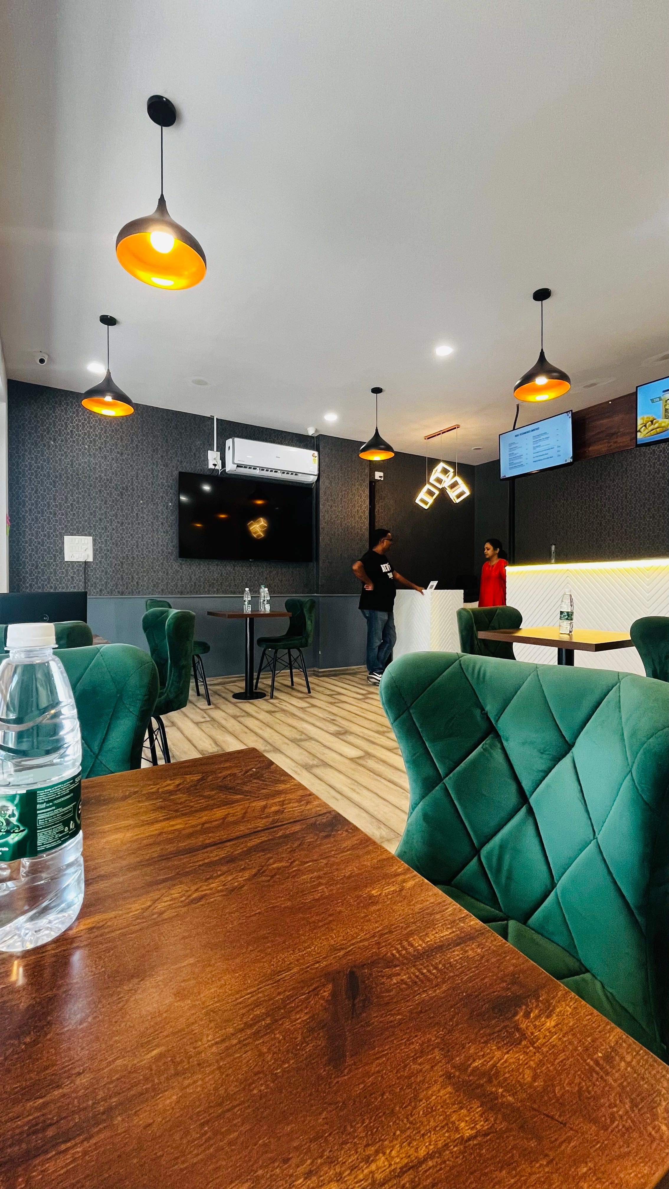 Seating area with green velvet chairs, patterned wall, and service counter