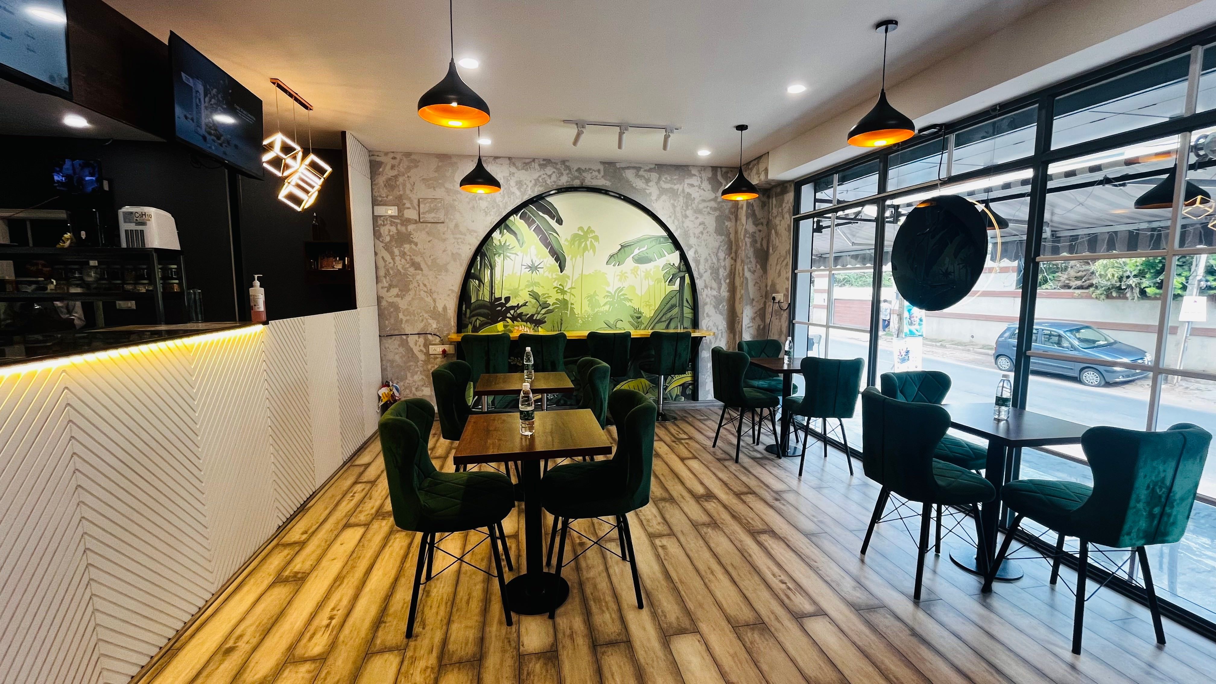 Interior with green velvet seating, arched tropical mural, and street-facing window